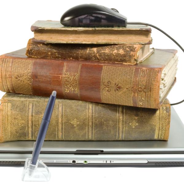 Old books piled on laptop.