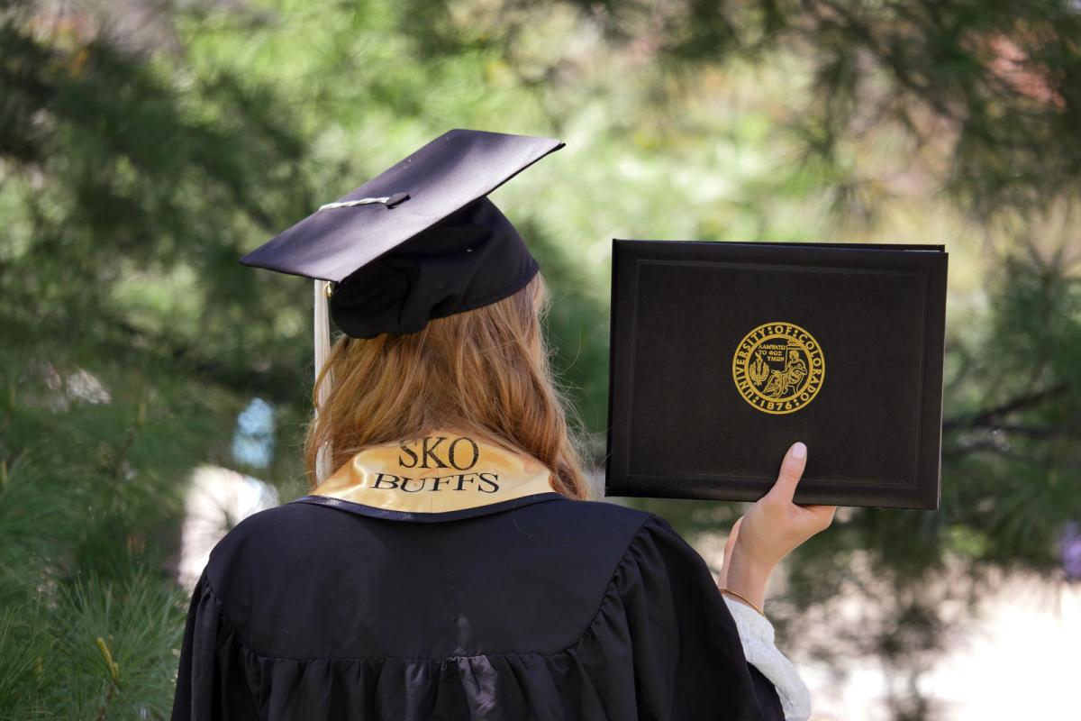 A graduate with a Sko Buffs stole and their diploma cover