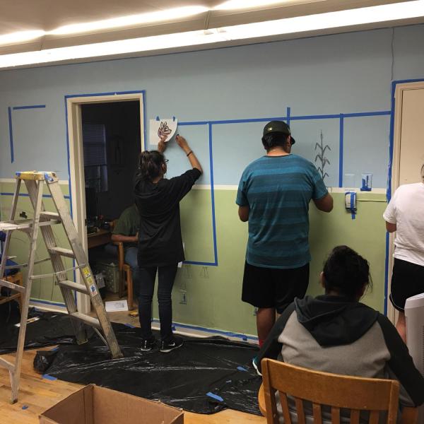students painting artwork on a wall together
