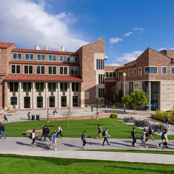 students walking across CU Boulder campus during passing period. The Visual Arts complex is visible in the background