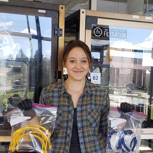 Rachel Sharpe holds up bags holding bands for face shields made with 3D printers on the CU Boulder campus.