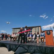 Donor Ann Smead cuts a ribbon lifted up by two flying drones.