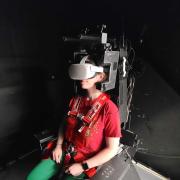 Graduate student Taylor Lonner dons a virtual reality headset inside the Tilt-Translation Sled, a machine that, in experiments, can mimic the motion of ocean waves.