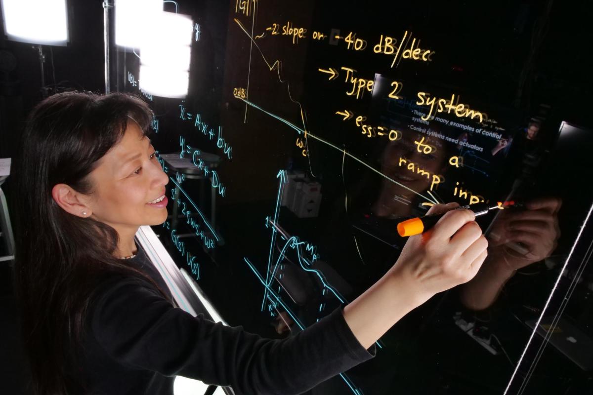 Professor writing equations on light board