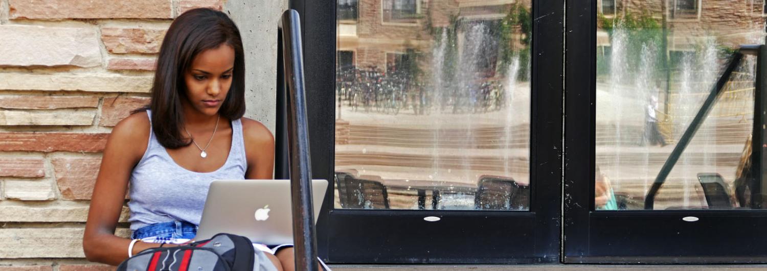 Female student studying outside a building