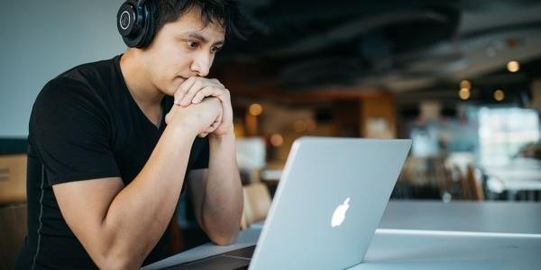 Man Wearing Headphones and Looking at Laptop