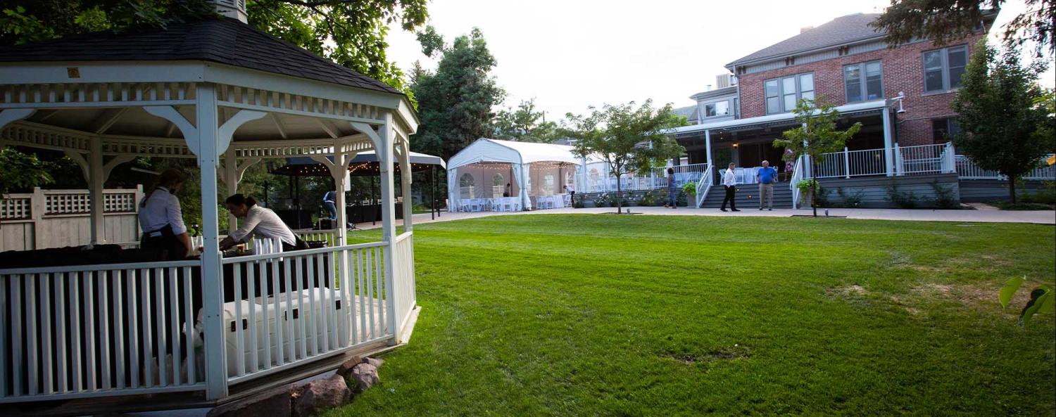 The green field and gazebo by the historic house on CU Boulder campus during an event