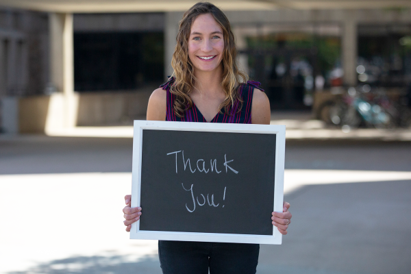 student holding chalkboard saying "thank you"