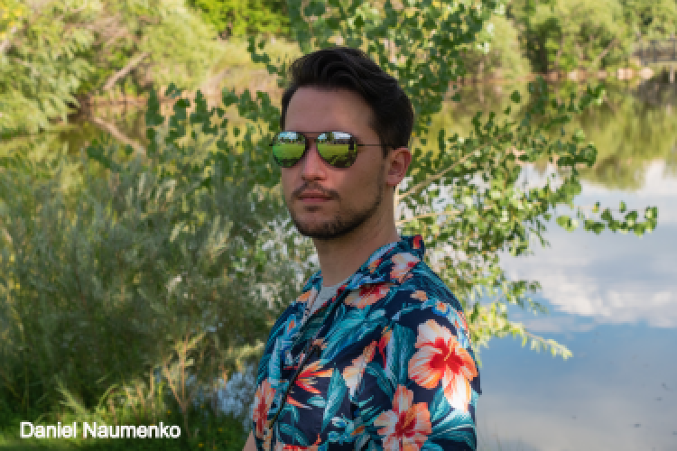 Daniel wearing sunglasses in front of a pond
