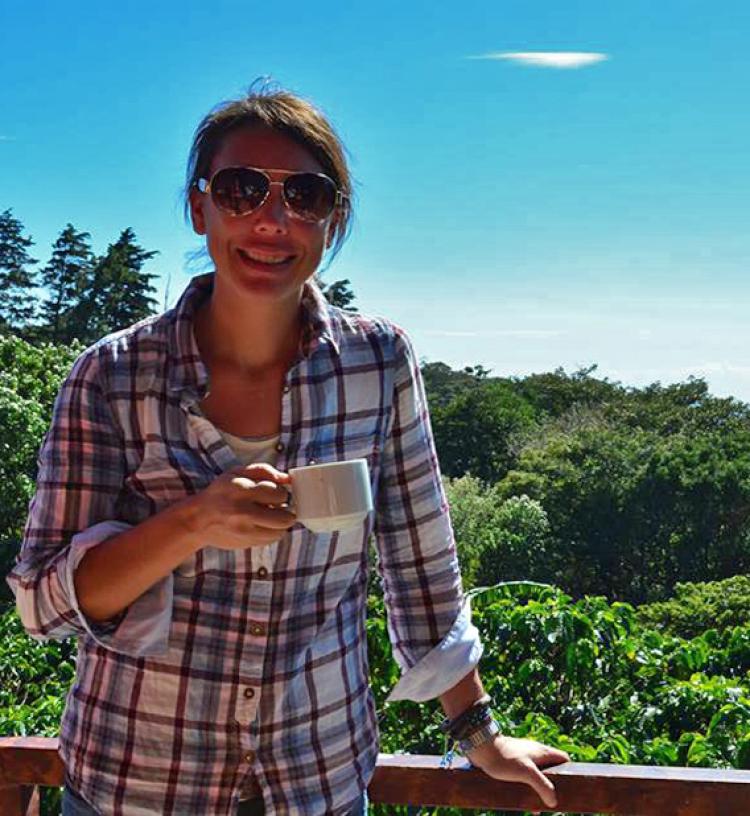Emily Hite standing on a deck holding a cup of coffee