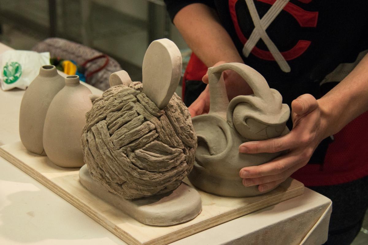 A student exhibits several pieces of pottery