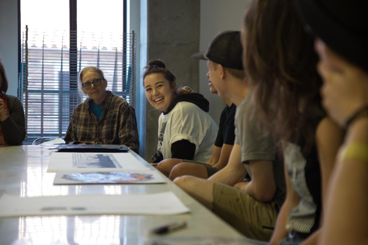 A student in an art class smiles during a discussion