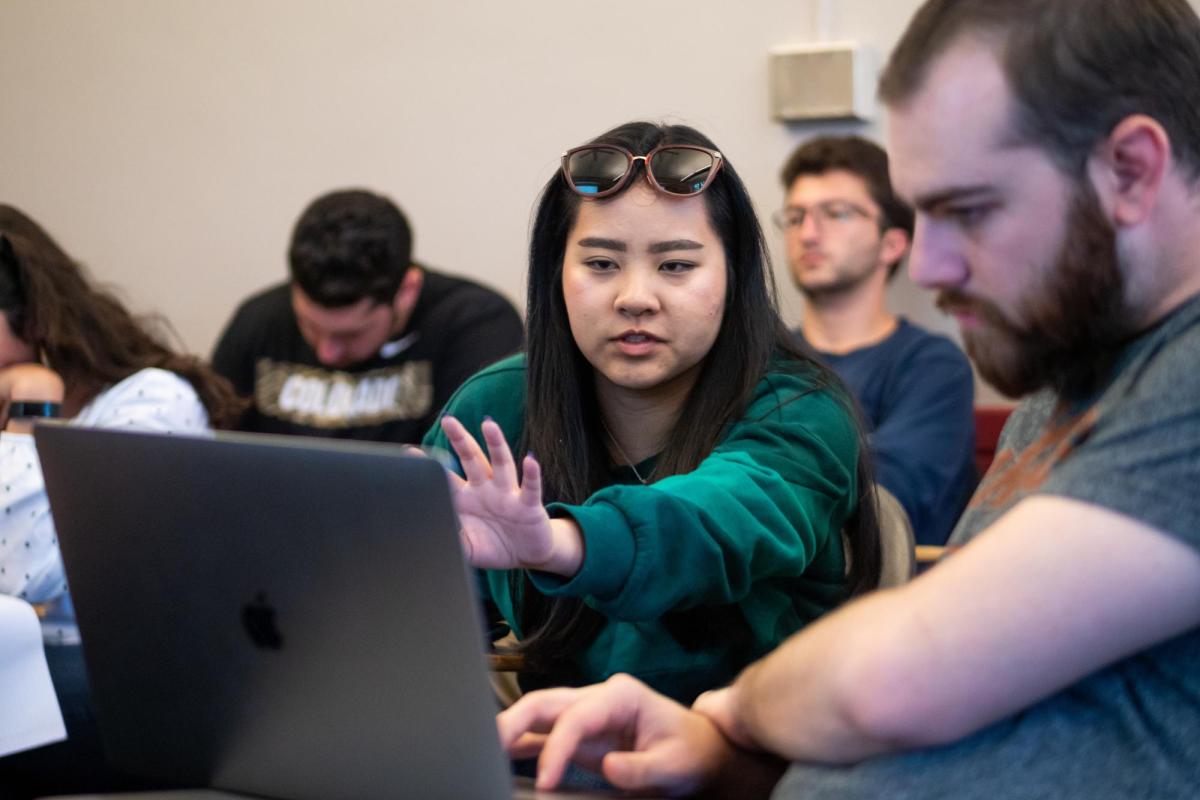 Two students gesture at a computer, seemingly immersed in a concept.
