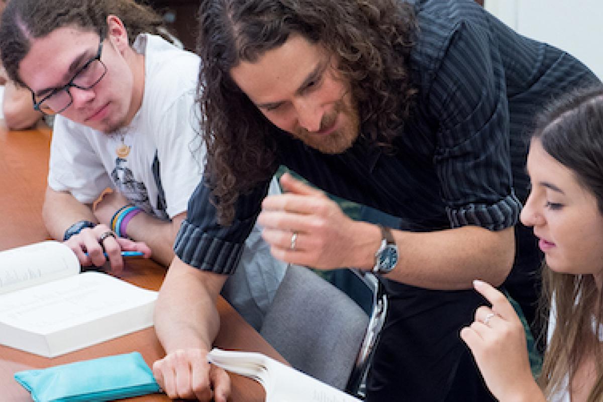 An instructor explains a concept to several students in a small seminar course.
