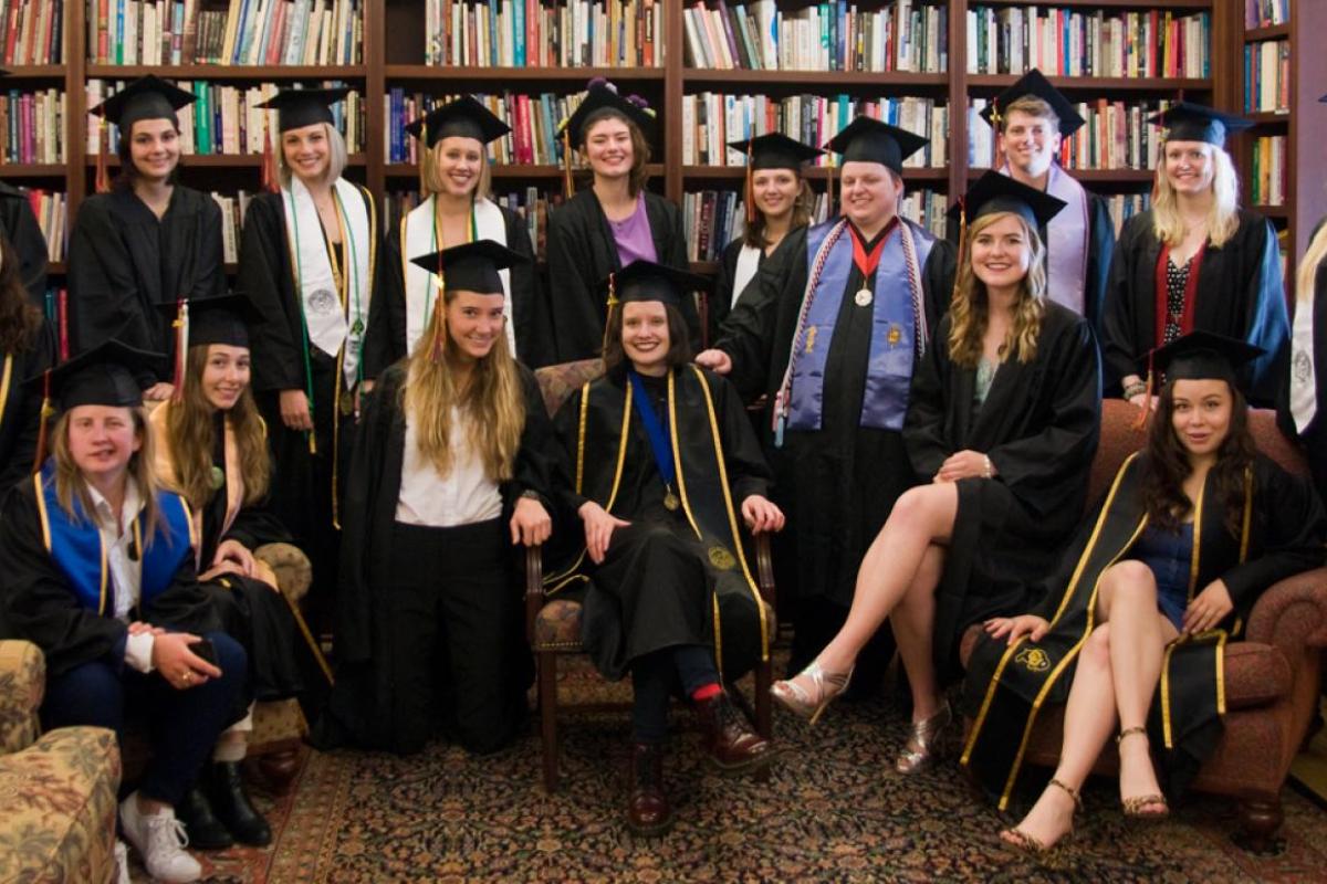 Graduates of the women and gender studies program smile in the Hazel Barnes library, where the major's offices are housed.