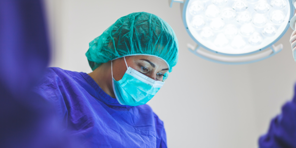 A surgeon works under the bright lights of an operating room.