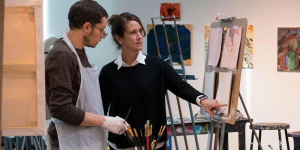 Student working with professor in front of an easel