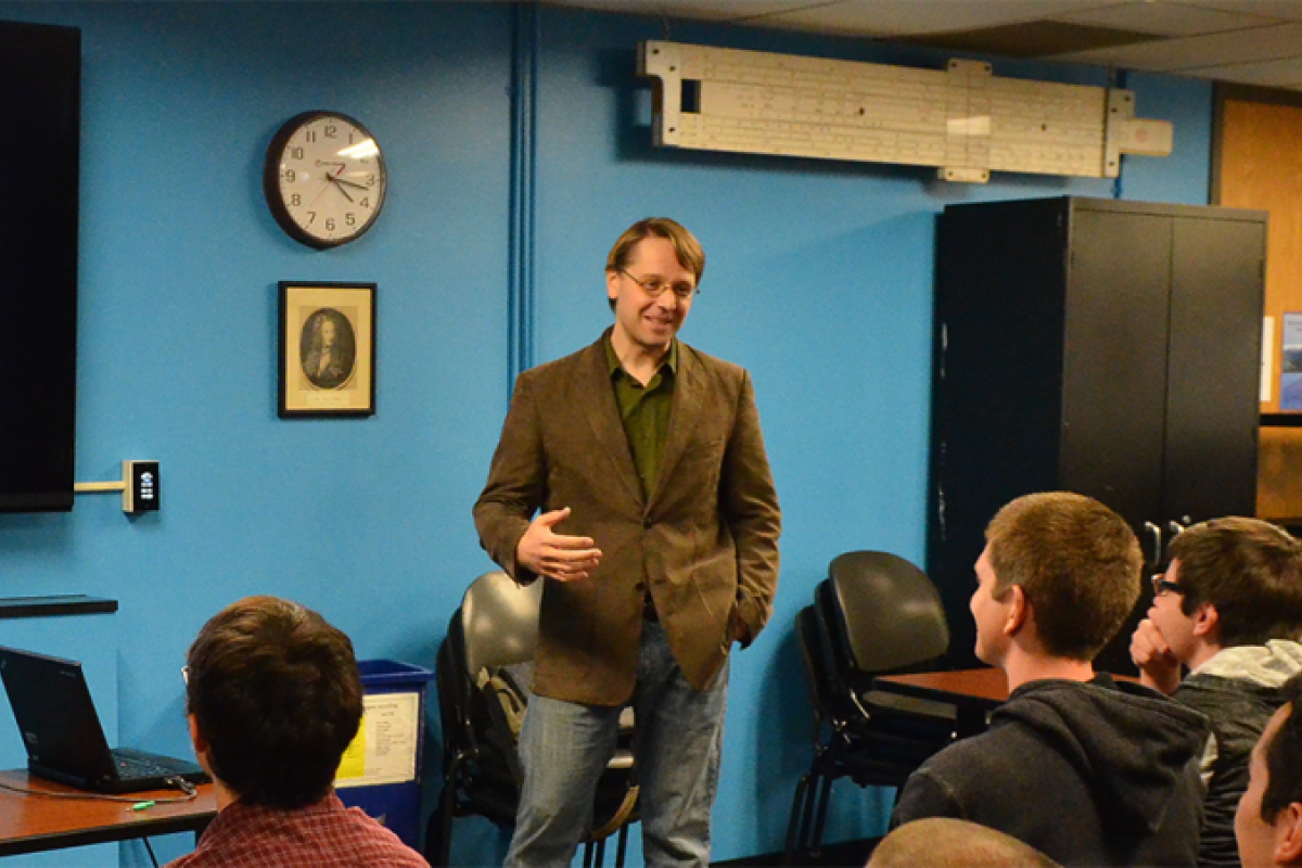 A faculty member stands in front of a screen explaining an applied math concept
