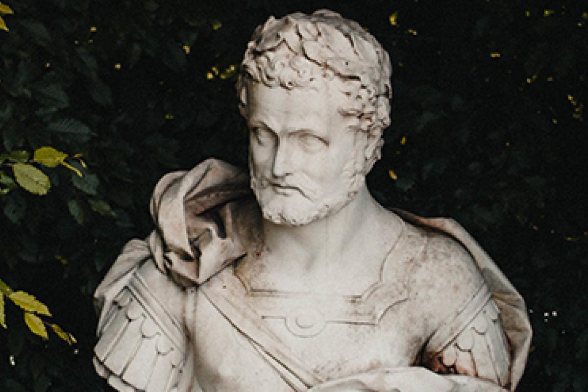 The bust of Marcus Aurelius in marble, sitting in a small garden.