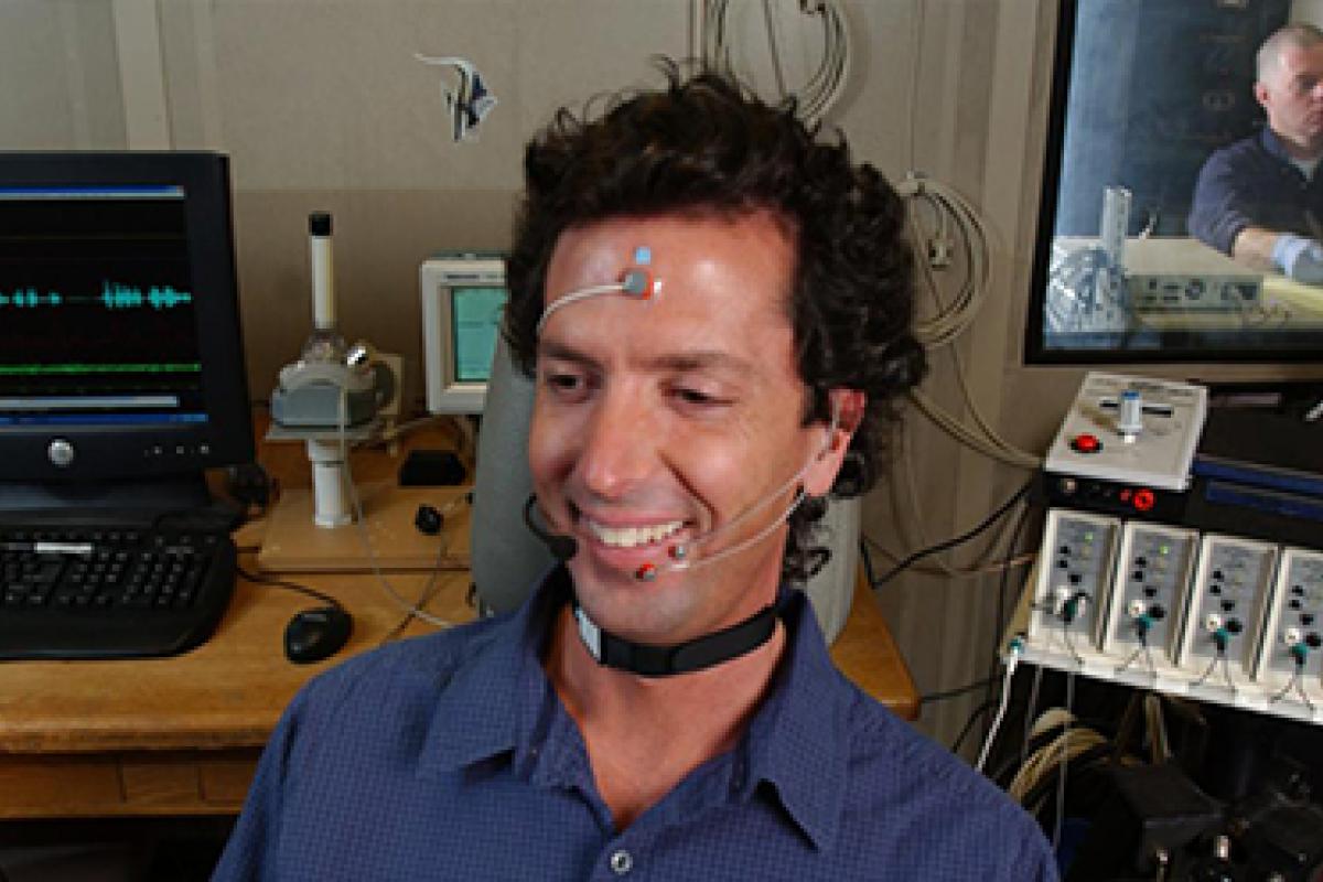 A man sits with research equipment surrounding to test its ability to change his hearing.
