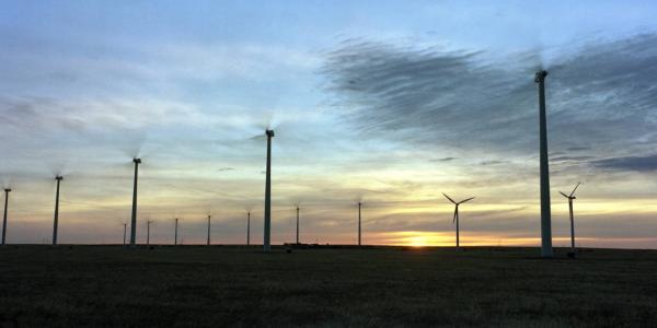 A bunch of wind turbines at sunset.