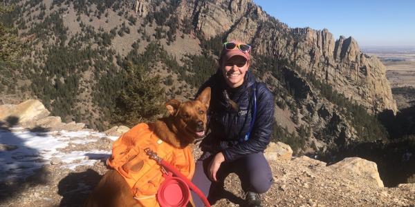Emily Kibby with a brown dog in mountains