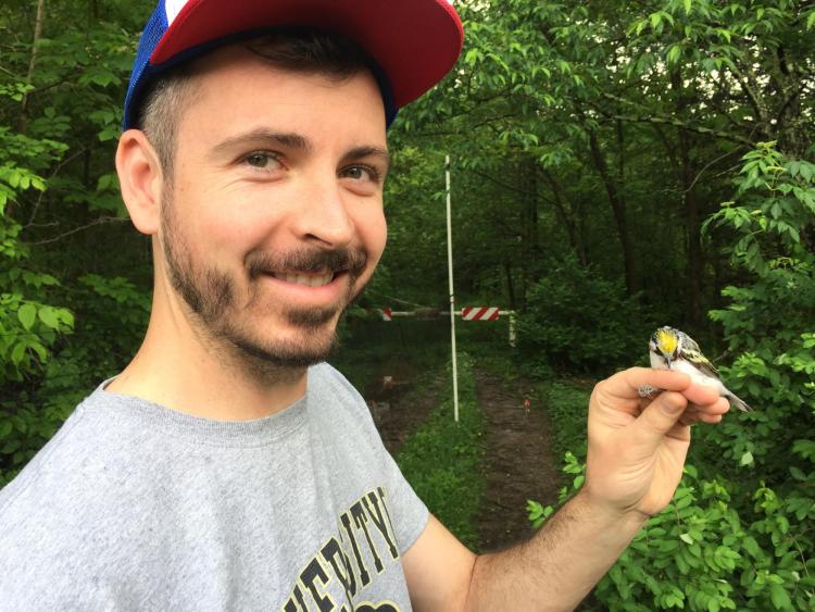 Photograph of Taylor holding a Chestnut-Sided Warbler