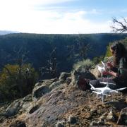 woman sitting atop rocks overlooking valley