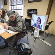 Students in conference room-style classroom, with one student on the Kubi.