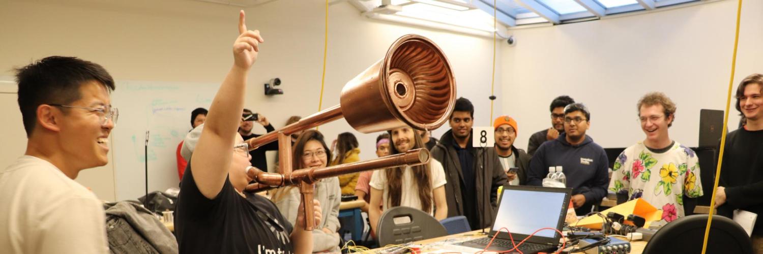 During the Moog Hackathon, Ruhan Wang demonstrates the e-trombone to the delight of other hackathon participants.