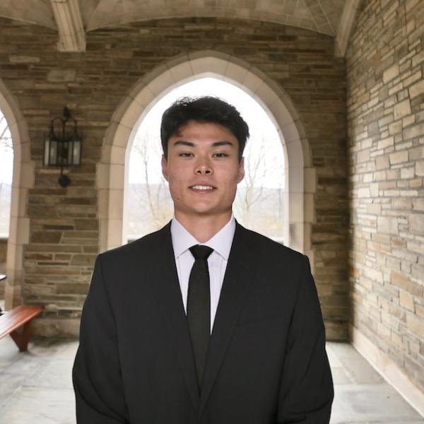 Jack Good wearing a suit standing outside under a stone archway