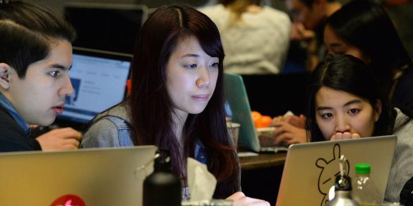 Photo of students coding together at T9Hacks