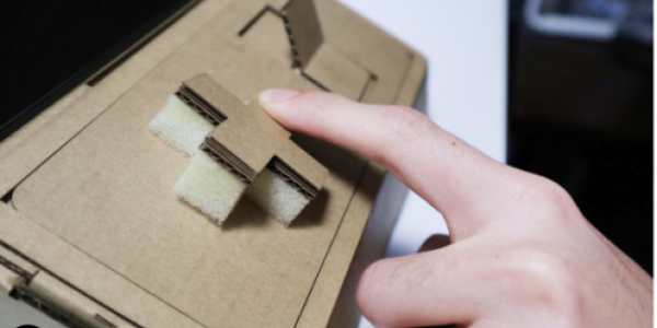 Two hands  playing on tinycade cardboard consoles