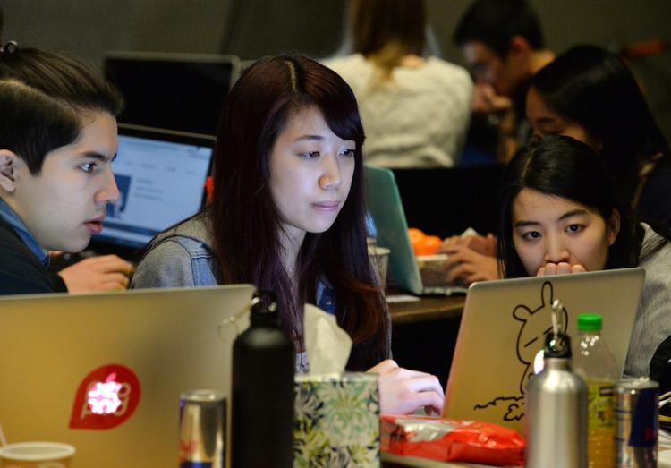 Three students looking at a computer screen while working together at T9Hacks