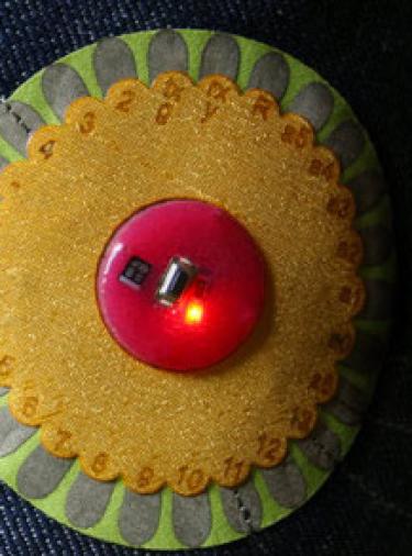 LilyPad Arduino with red light in the center .