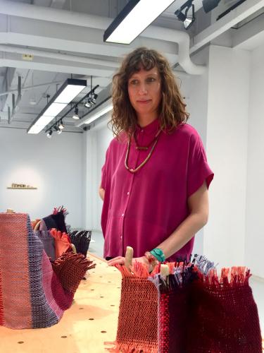 Etta Sandry stands next to rolled-up fabric.