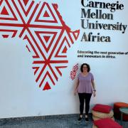 Aileen Pierce stands in front of a CMU Africa sign