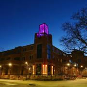 The tower of the Roser ATLAS building lit with a magenta light.
