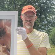 Kevin holding a piece of his artwork while standing in front of the Flatirons.