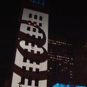 Screenshot of CBS video featuring @ sign projection on building