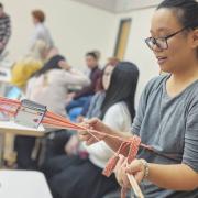 Shanel Wu demonstrates tablet weaving at a research showcase for human-computer interaction and information science.
