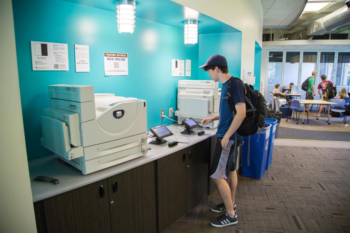 male student waiting for paper to print
