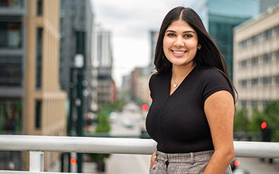 Isha stands in front of the Denver skyline.