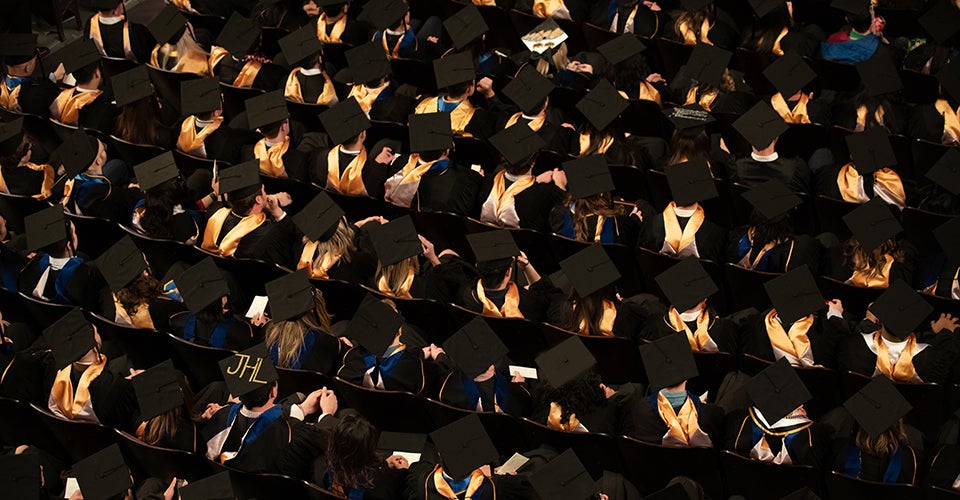 Business school graduates, from above, sit at a graduation ceremony.