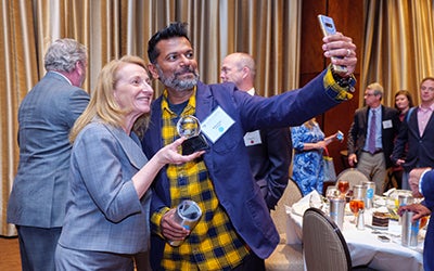 Two people take a selfie holding the award.