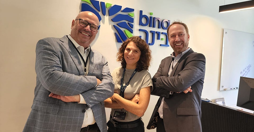 Three professionals pose as they stand together in a lobby.