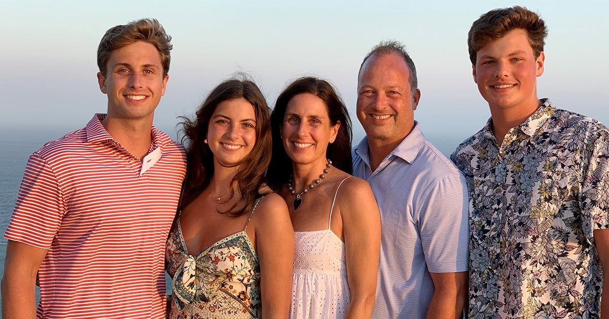 A family of five poses on a beach at sunset.