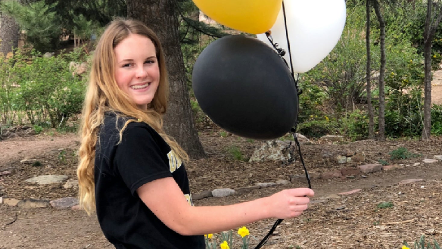 Image of Jordyn holding a collection of CU themed balloons