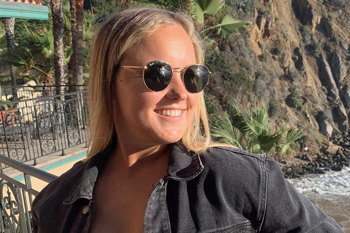 Megan in sunglasses and a luxury jacket along the California coast.