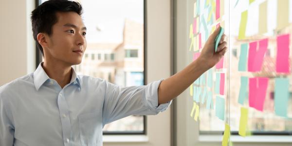 man pointing to post-it notes on wall